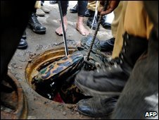 Searchers lift an officer's body from a manhole near the mutineers' barracks in Dhaka, 27 February